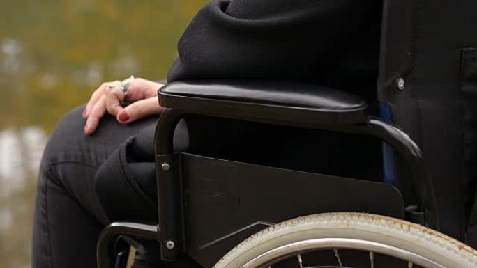 残疾，悲伤，孤独-坐轮椅的女人的手在湖上