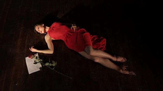 一个穿着红色连衣裙的年轻时尚女孩死于躺在地板上的不快乐的爱情。