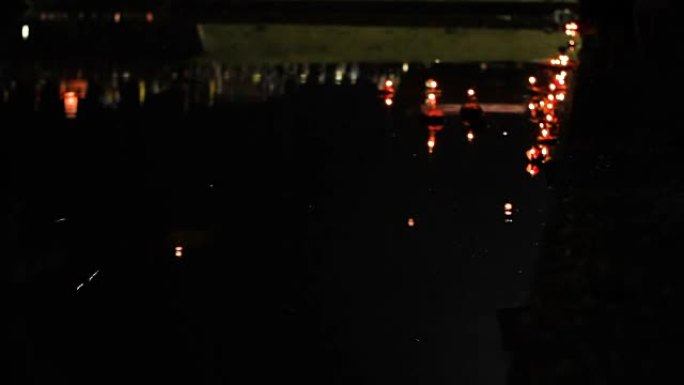 当地人和游客庆祝Loi kathong。人们放下蜡烛的花圈，放上天堂中国纸灯笼。背景模糊。泰国普吉岛