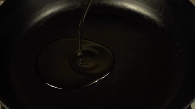 葵花籽油在加热的铸铁锅上流动。慢动作。