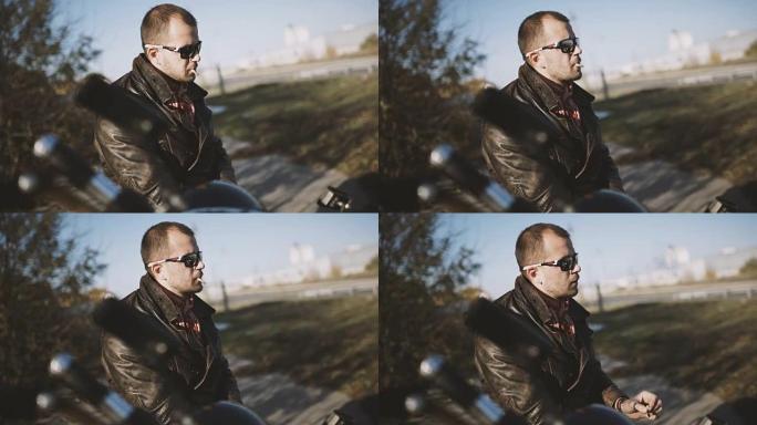 年轻的摩托车手坐在摩托车上抽烟