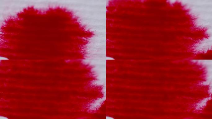 白色宏观背景的羊皮纸上溅出红色的血。红色墨水溅满了水和颜色