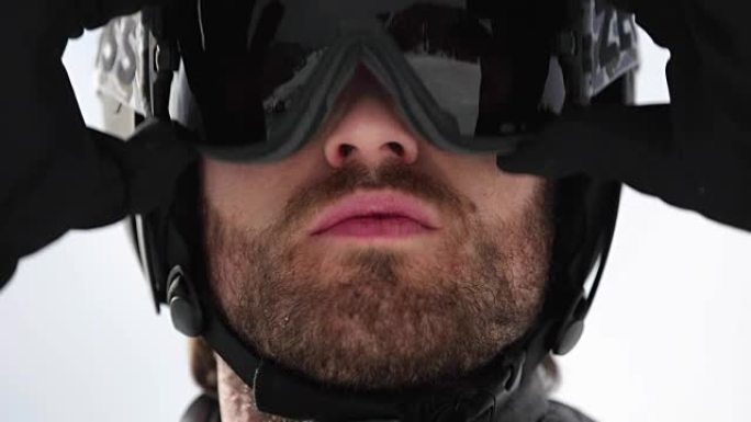 男子脸部细节调整头盔准备滑雪。登山滑雪活动。冬季滑雪者在高山户外运动。前视图。慢动作60p全高清视频