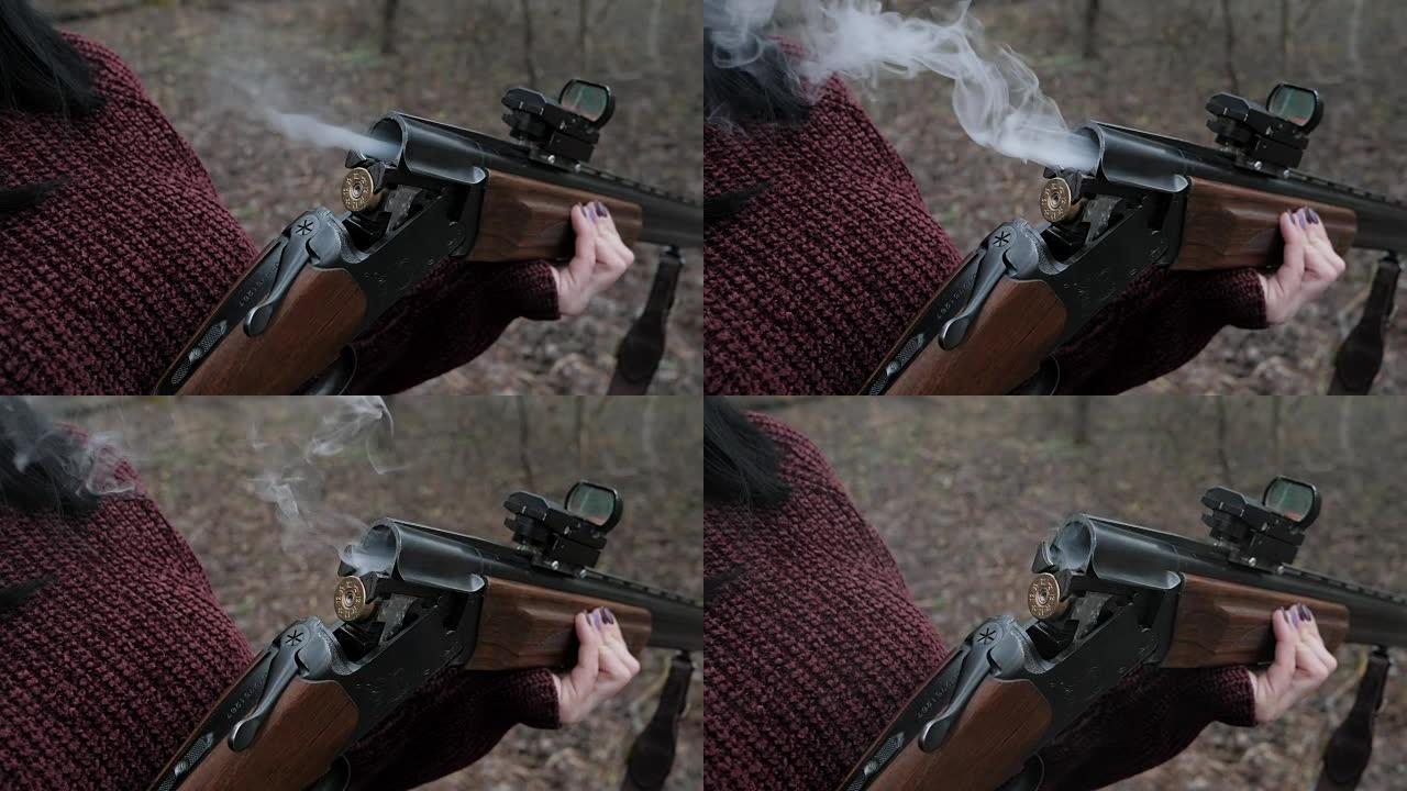 穿着勃艮第保暖衣服的猎人女人从枪中取出子弹。发射后，从滑膛猎枪的树干冒烟。慢动作