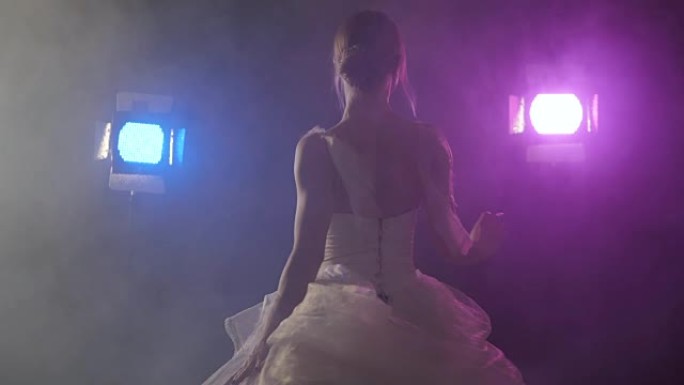 性感的芭蕾舞演员，穿着古典或现代芭蕾舞的白色短裙舞蹈元素，在黑暗中旋转，泛光灯背景上有蓝色和紫罗兰色
