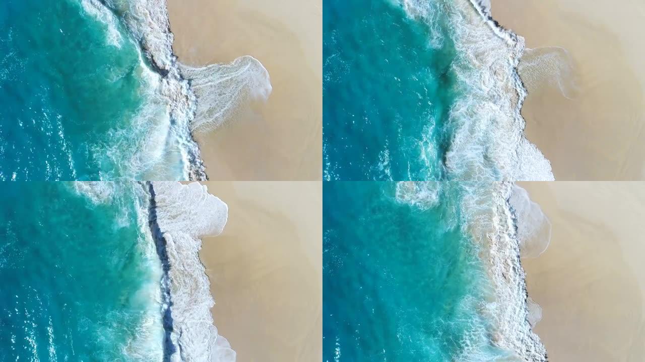 4k无人机镜头在海滩上撞击海浪的鸟瞰图。