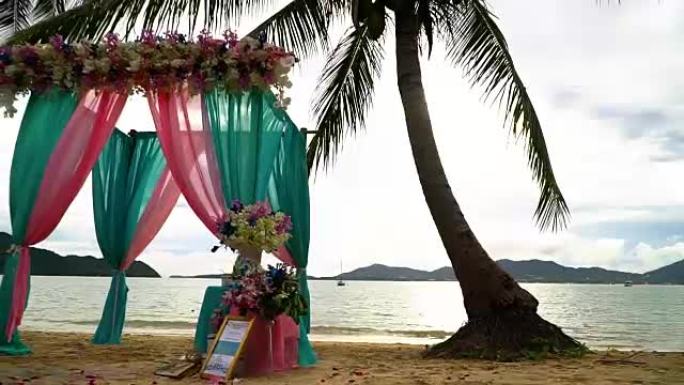 美丽的婚礼装饰和拱门在棕榈树之间的海滩上。