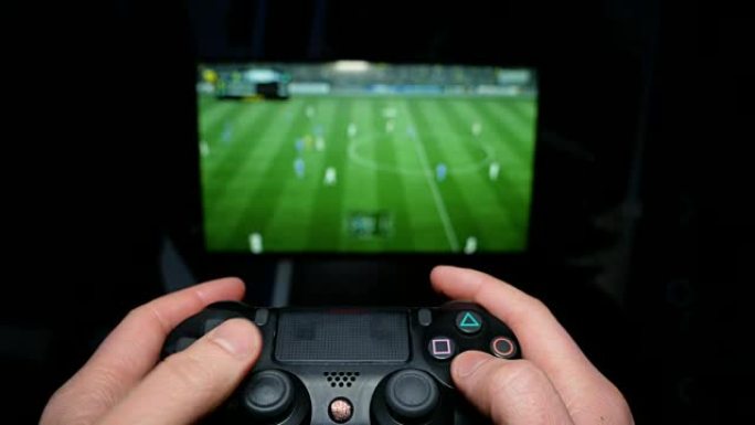 在电视背景上的操纵杆上播放人手。虚拟足球比赛。玩家对电脑游戏很生气。