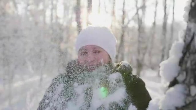 女孩走在冬天的树林中，扔雪，微笑，大笑。在新鲜空气中散步。