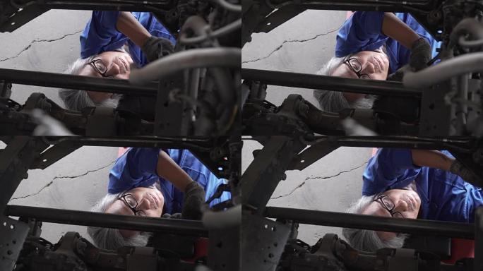 多莉从顶视图拍摄: 亚洲高级汽车修理工在车辆下工作
