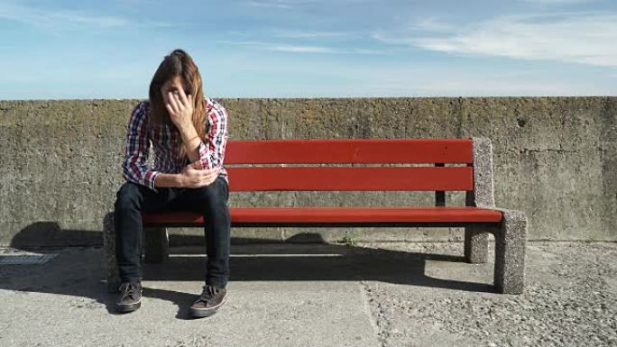 一个人独自坐在长凳上，忧心忡忡，情绪低落4K