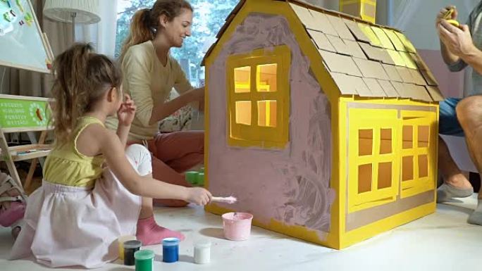 Young family with child building and painting toy 