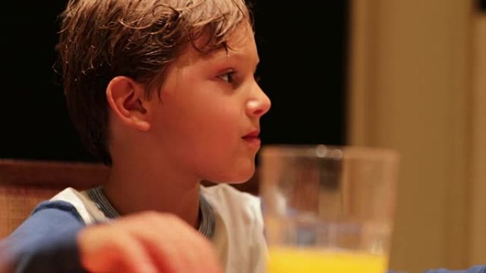 坦率的现实生活中，孩子在餐桌上的瞬间将橙汁杯放在他旁边，并注意周围发生的社会动态