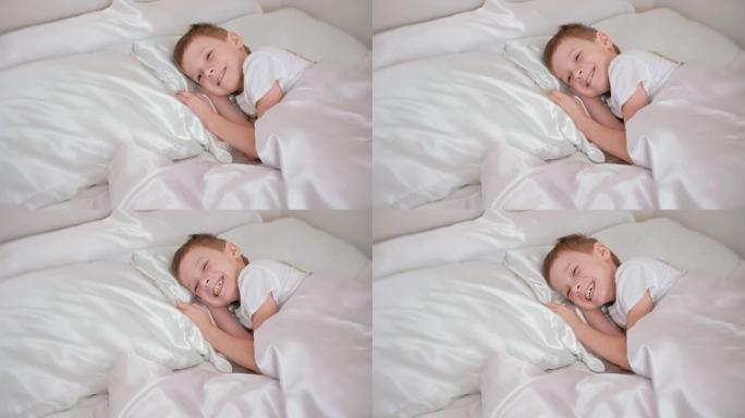 七岁的男孩刚醒来，躺在床上大笑。