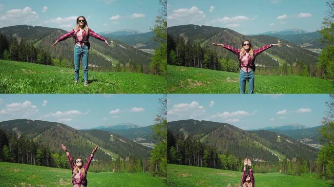 一位年轻的白人妇女背着背包和太阳镜站在山顶上，举起双手。个人成长，克服业务困难，个人动机，自由和自我
