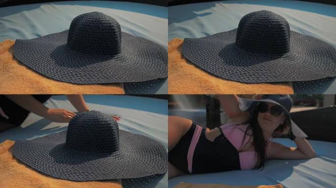 美丽的女孩正戴上蓝色的帽子，躺在躺椅上。夏日的阳光。