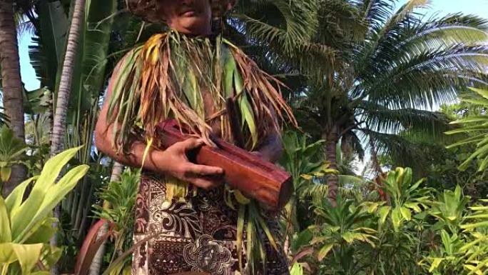 太平洋岛民男子在一个小的木棍鼓上玩耍