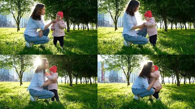 日落时，母亲带着婴儿在公园里嗅着一朵花。小女儿向母亲要把手，慢动作。
