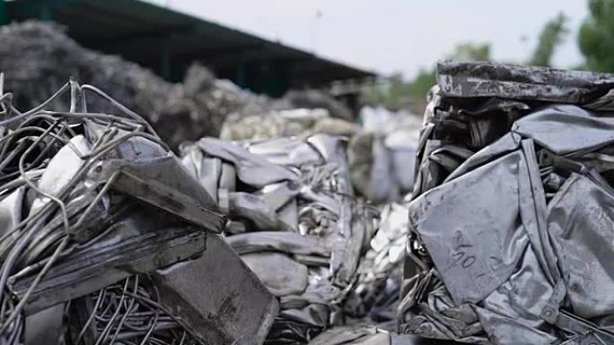 在阴天的夏日，大型压制煤球和金属废料躺在垃圾场的室外