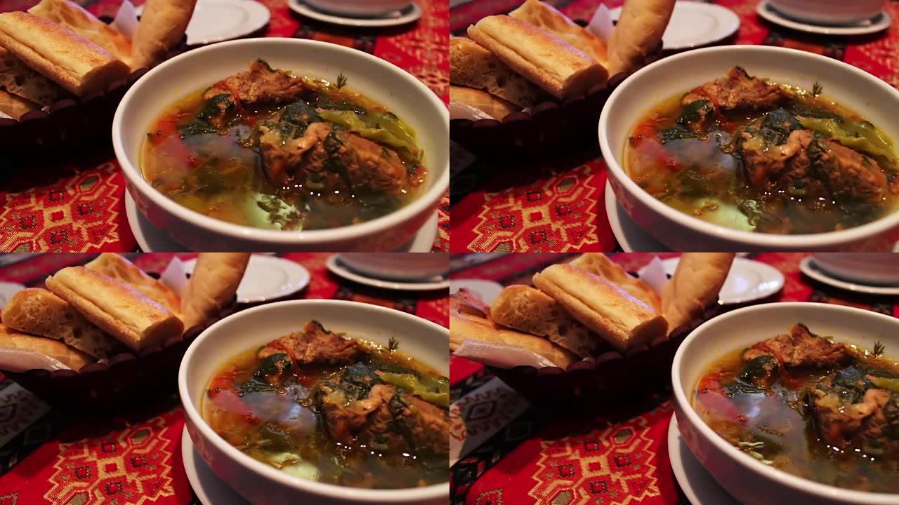 餐厅里美味的阿塞拜疆国家羊肉汤。肉汤在面包玉米饼的背景下放在白色盘子里