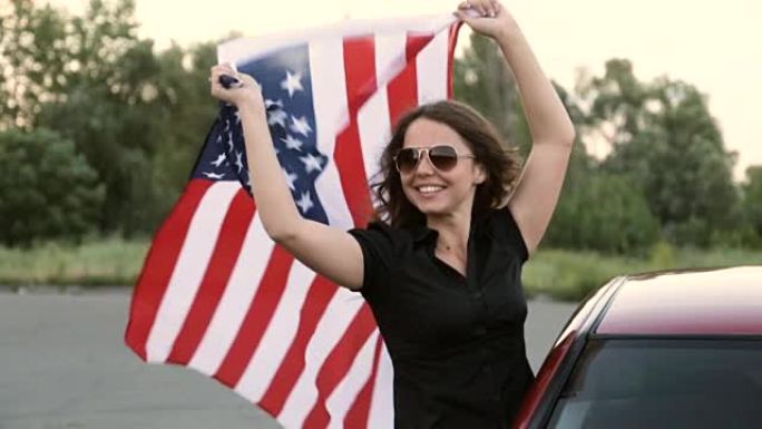 手里拿着美国国旗的快乐女孩。红色的车