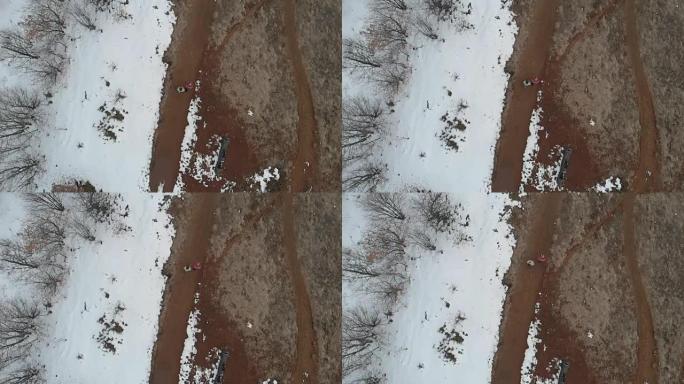 空中: 夫妇在雪地和树木的乡间小路上行走，直接在视野上方，慢动作