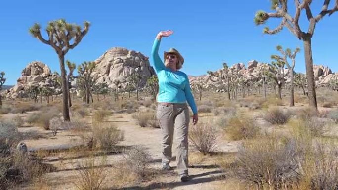 一名戴牛仔帽的女子挥手走过莫哈韦沙漠中部