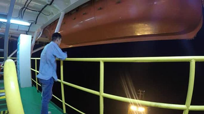 男子站在海上石油平台上，晚上望向大海。