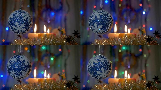 圣诞树上挂着一个蓝色的大球。新年和圣诞装饰品。燃烧蜡烛。闪光花环。背景模糊。