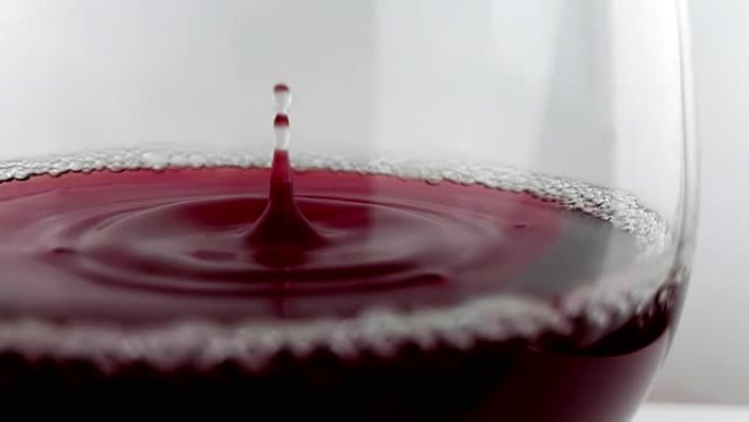 红酒掉落在白色背景上的酒杯中，营养保健概念，用高速相机拍摄