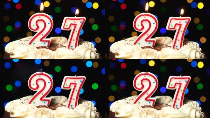 蛋糕上的27号-27岁生日蜡烛燃烧-最后吹灭。彩色模糊背景