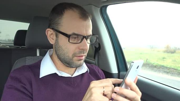 商人坐在车内使用智能手机。车上有智能手机的人。