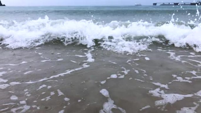 慢镜头碧波荡漾在沙滩上，雨点落下