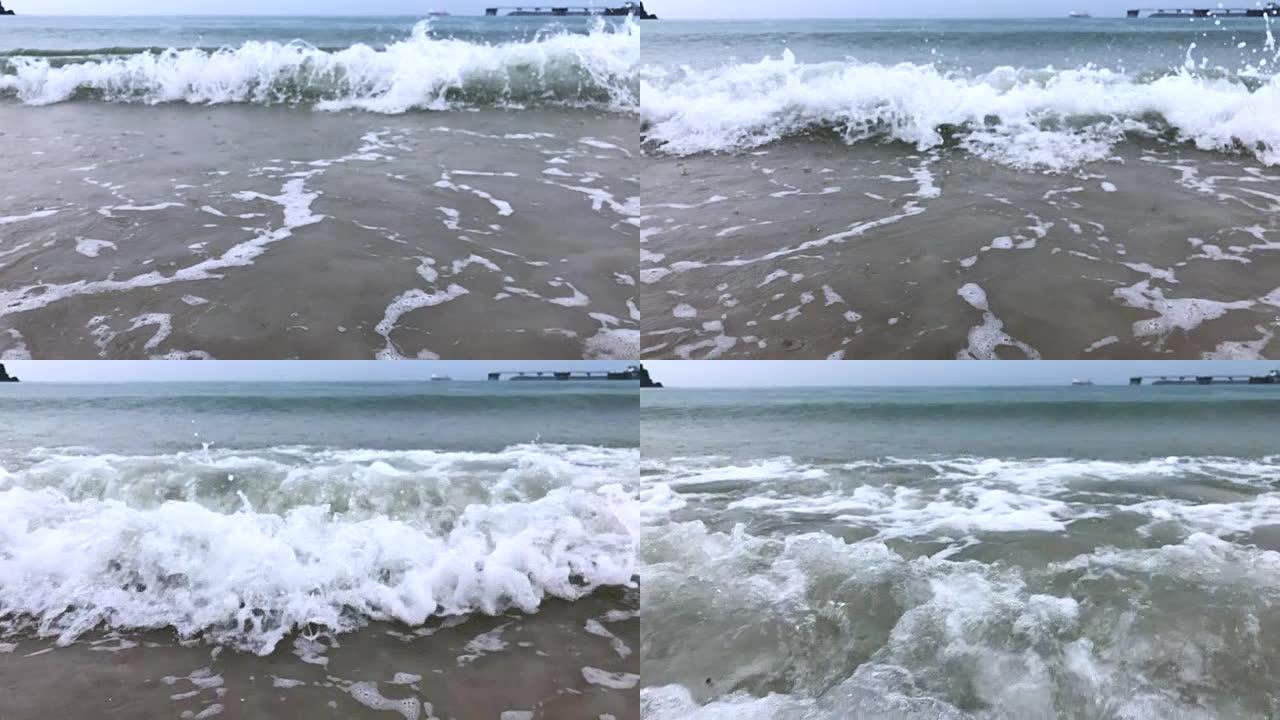 慢镜头碧波荡漾在沙滩上，雨点落下