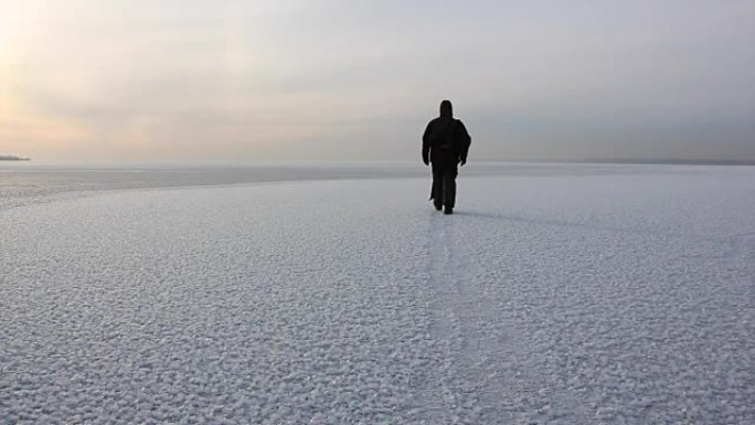 俄罗斯西伯利亚Ob水库日落时，穿着暖和衣服的人在冰冻的河上行走