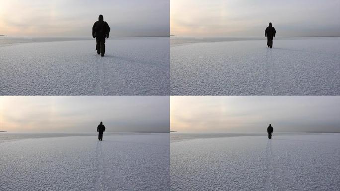 俄罗斯西伯利亚Ob水库日落时，穿着暖和衣服的人在冰冻的河上行走