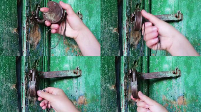 门上的老式铁锁已被绿色油漆剥落。母手开启和关闭锁