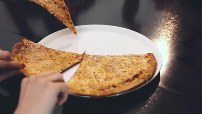 人类的手，从盘子里拿出零碎的美味披萨。特写
