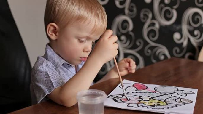 儿童用画笔和颜料绘画的特写。