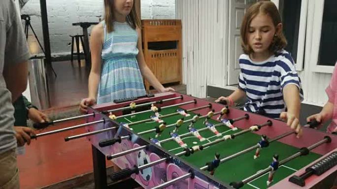 一个年轻的未成年女孩和她的朋友玩桌上足球