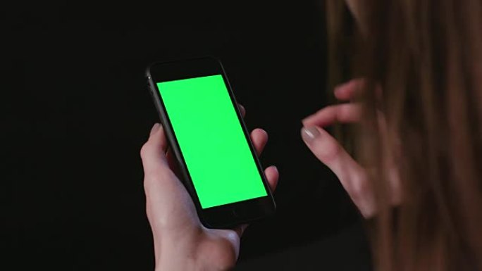 女人拿着绿屏放大的手机
