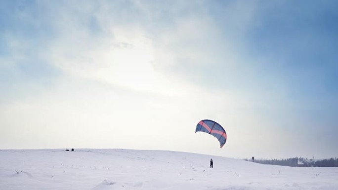 一个带着飞行降落伞的人正在做雪景，然后掉在雪中。冬天有风筝的快乐男性有美丽的背景