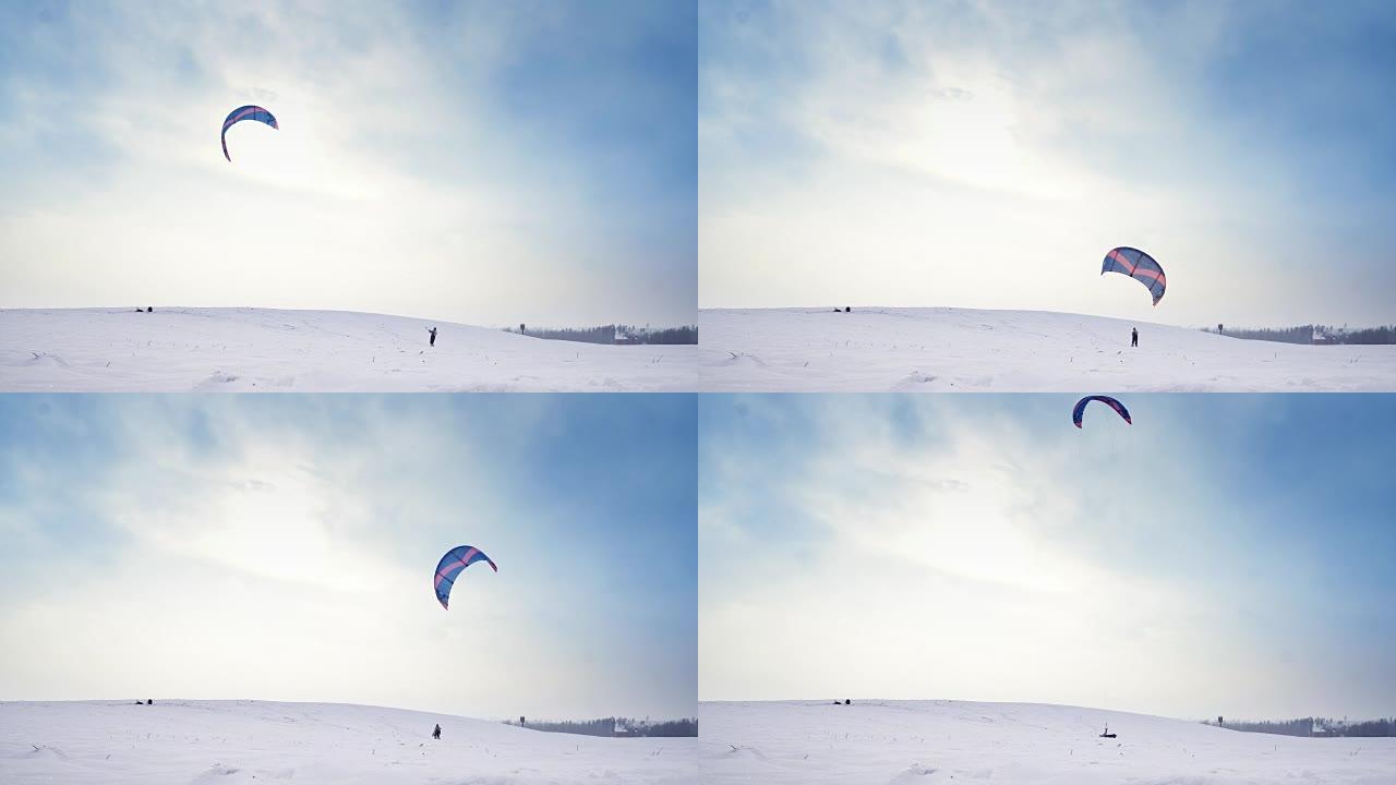 一个带着飞行降落伞的人正在做雪景，然后掉在雪中。冬天有风筝的快乐男性有美丽的背景