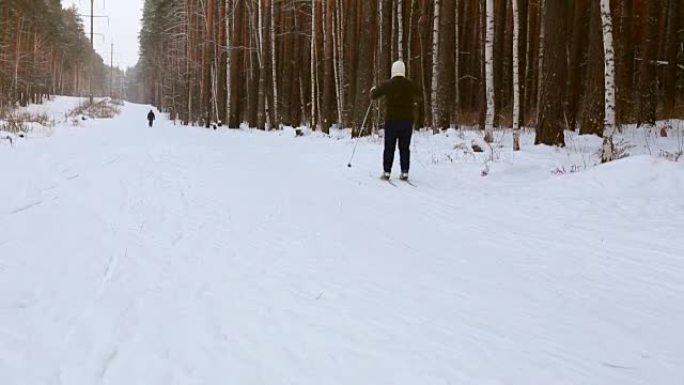 Skier moving along ski-track through the winter pi
