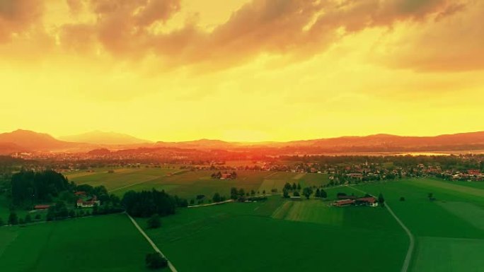 德国巴伐利亚巴伐利亚阿尔卑斯山的绿色欧洲田野、金色天空、黄昏的惊人鸟瞰图。