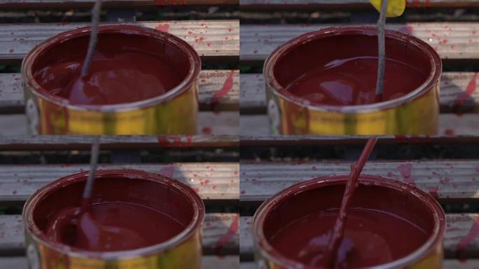 搅拌罐子里的红色油漆，在银行棍子里混合油漆，慢动作