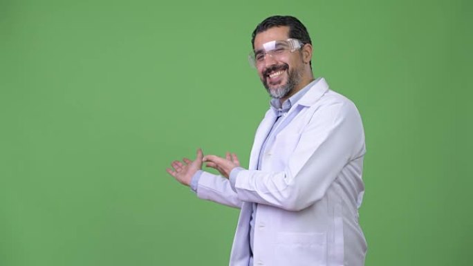 英俊的波斯大胡子医生戴着防护眼镜，展示了一些东西