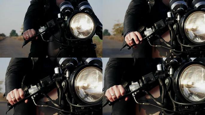 前面的观点，一个不认识的人在黑色皮夹克骑摩托车在乡村道路上。大灯打开了