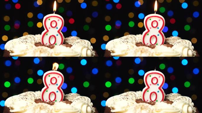 蛋糕顶部的8号 -- 八根生日蜡烛燃烧 -- 最后吹灭。彩色模糊背景