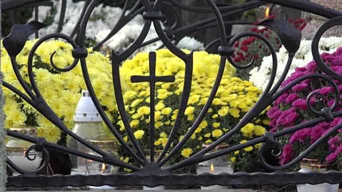 蜡烛淡黄色菊花在金属十字架在墓地。FullHD